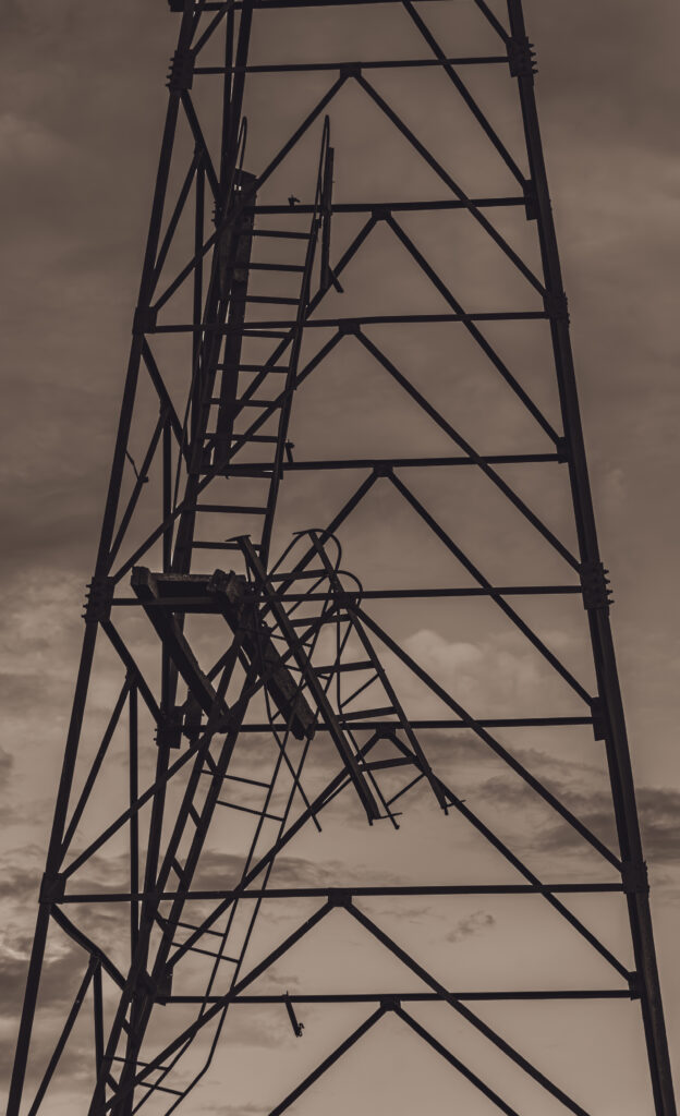 A derelict watchtower standing in a decaying building, captured amidst overgrown vegetation and worn-out structures / Hõõguv vaatetorn lagunevas hoones, jäädvustatud üle kasvanud taimestiku ja kulunud struktuuride keskel