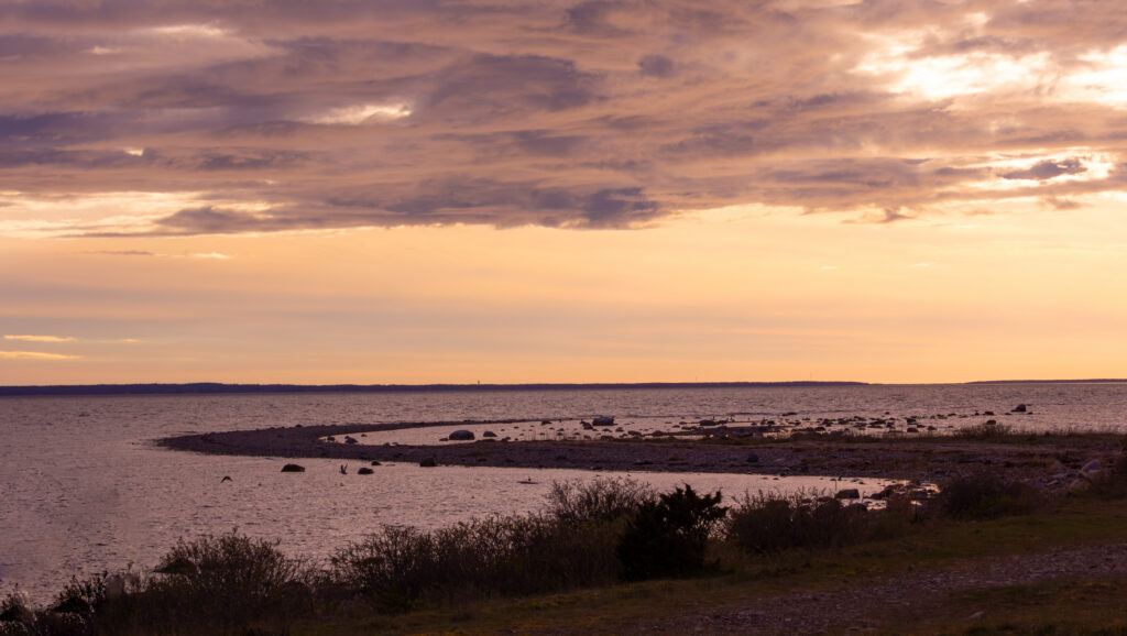 A stunning landscape shot of the sea with a strip of land curving into the water in an S-shape at sunset in Estonia / Pimestav maastikufoto merest, kus maasõõr, mis kulgeb vee sisse S-kujulise kurviga, jäädvustatud päikeseloojangul Eestis