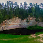 Sandstone cliffs of Suur and Väike Taevaskoda rising above the Ahja River in a lush Estonian forest