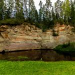 Sandstone cliffs of Suur and Väike Taevaskoda rising above the Ahja River in a lush Estonian forest