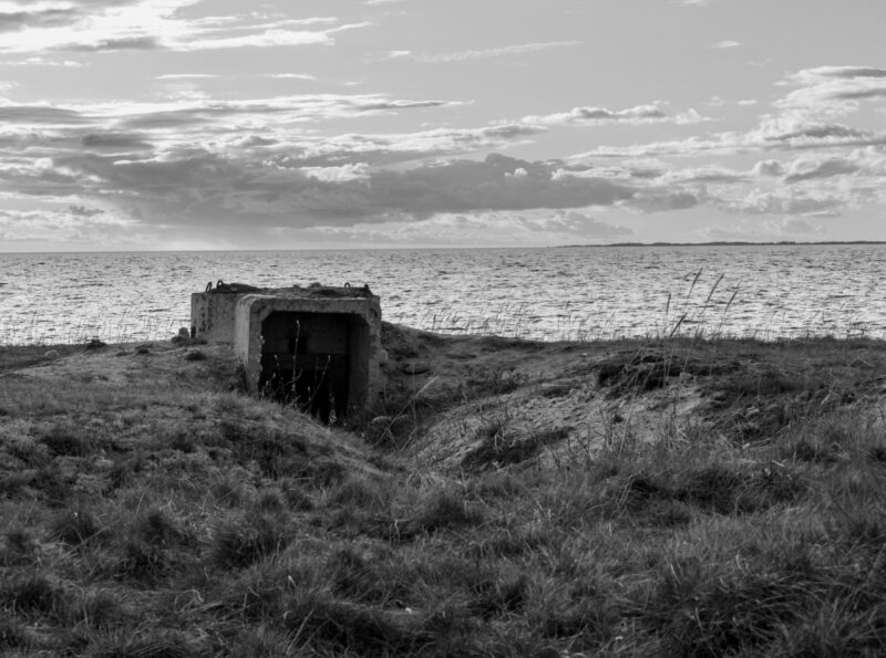 A derelict bunker near the sea in Estonia, surrounded by coastal vegetation and the vast seascape / Lagunenud punker Eesti rannikul, ümbritsetud rannataimestikust ja avarast meremaastikust