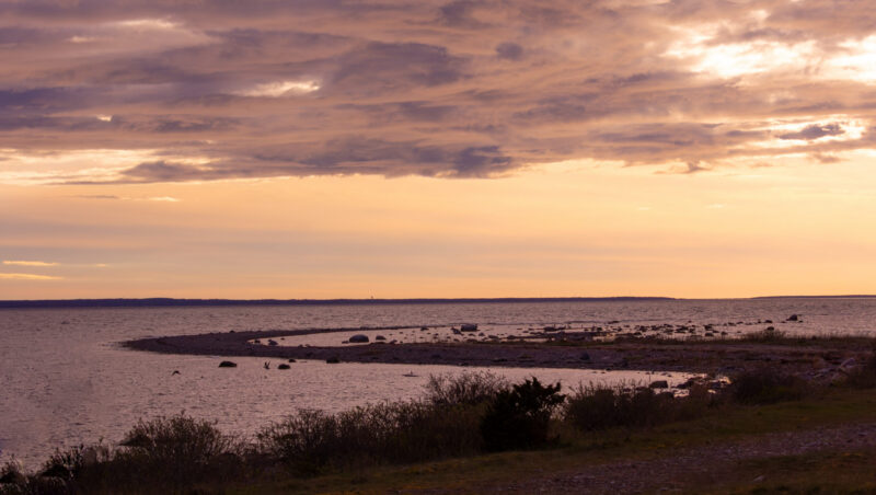 A stunning landscape shot of the sea with a strip of land curving into the water in an S-shape at sunset in Estonia / Pimestav maastikufoto merest, kus maasõõr, mis kulgeb vee sisse S-kujulise kurviga, jäädvustatud päikeseloojangul Eestis