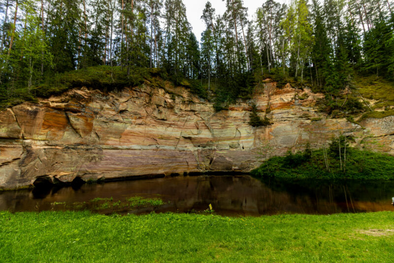 Sandstone cliffs of Suur and Väike Taevaskoda rising above the Ahja River in a lush Estonian forest